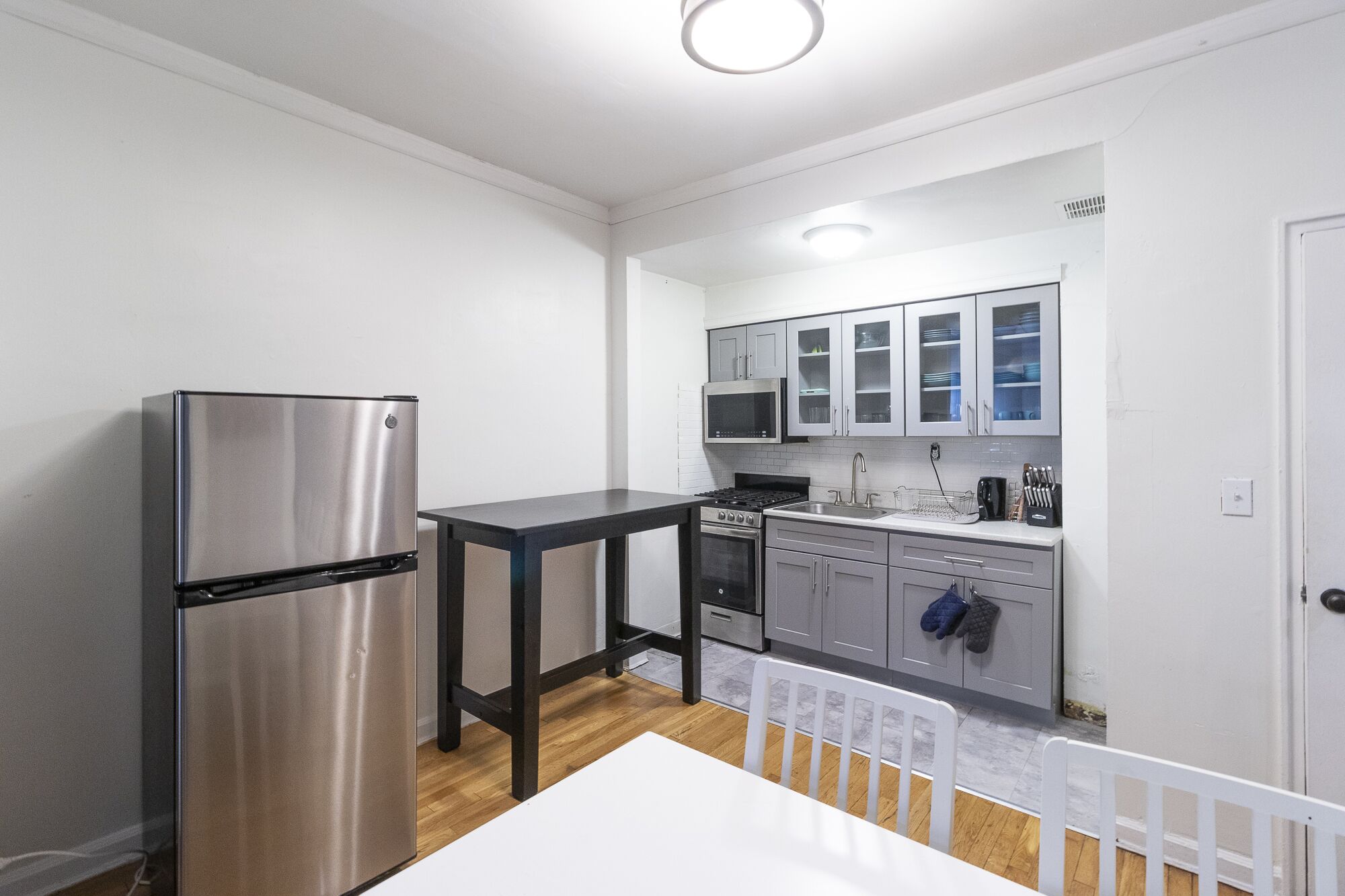 A compact kitchen with a stainless steel refrigerator, a microwave, and a stove.