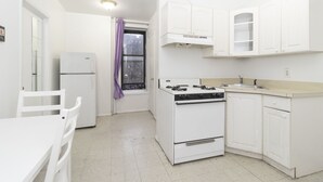 A compact kitchen with white cabinets, a stove, and a refrigerator.