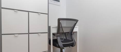 Una oficina en esquina con un escritorio, una silla y un archivador.