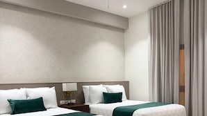 Habitación de hotel con dos camas, ventilador de techo, escritorio y una silla.