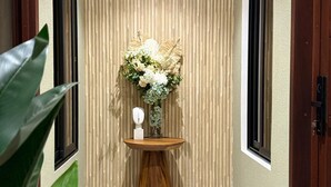 Un pasillo con piso de madera, un arreglo floral en la pared y dos puertas.