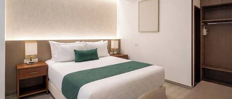 A hotel room with a bed, bedside tables, a desk, and an air conditioning unit.