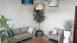 Una sala de estar moderna con un sofá, dos sillones, una mesa de centro y plantas decorativas.