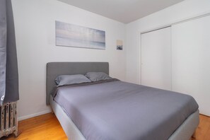 Un dormitorio con cama, radiador, cuadro y armario.