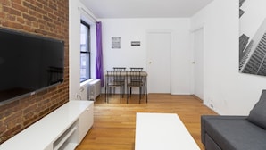 A compact living space with a television, a dining table with chairs, a sofa, and a fireplace.