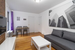 A modern living room with a white coffee table, grey sofa, and a cityscape mural.