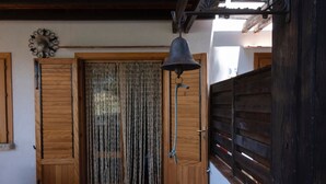 A wooden door with a rope barrier, a hanging bell, and a decorative metal piece above the door. - Casa Sally with sea view in Macari (San Vito Lo Capo)