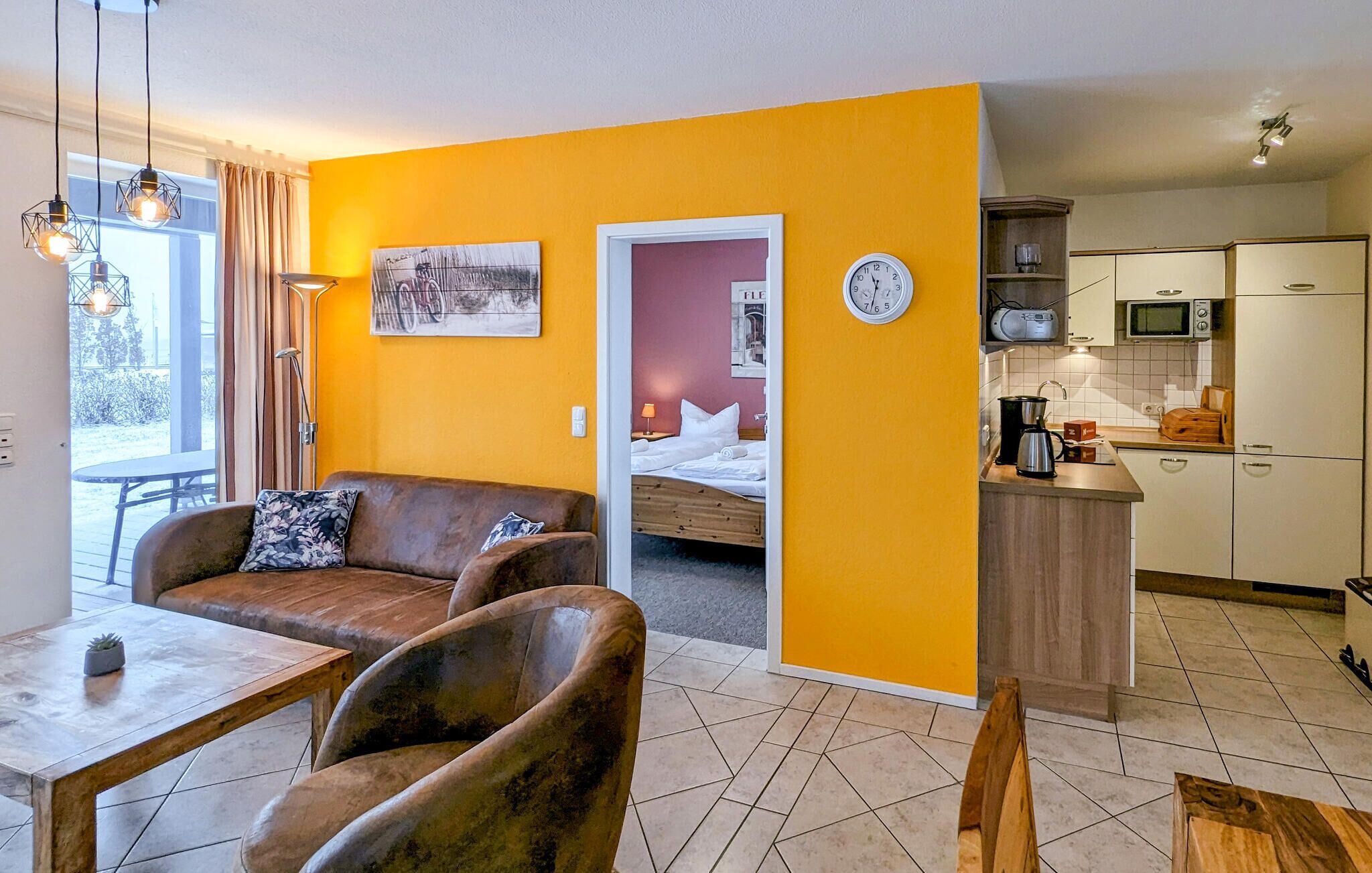 A compact living space with a sofa, a dining table, a kitchen area, and a bed.
