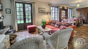 Un salon chaleureux avec un canapé, une table basse, des fauteuils en osier et un coin repas comprenant une table et des chaises.