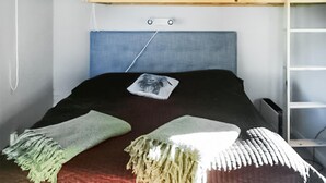 Una cama individual con literas, un cabecero azul, una mesita de noche pequeña y un edredón individual.