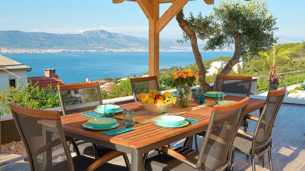 A wooden table set for dining with a view of the sea and mountains. - Beautiful home in Mastrinka (Mastrinka)