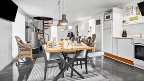 A modern kitchen with a wooden dining table, black chairs, and a spiral staircase.