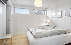 Ein Schlafzimmer mit einem Bett, einer Bank und zwei Fenstern.