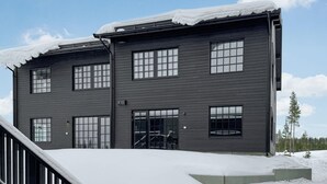A two-story building with a dark exterior, large windows, and a snow-covered roof. - Stunning apartment in Idre with sauna (Idre)