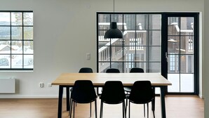 A modern dining area with a wooden table and black chairs, large windows with a view of a snowy landscape, and a black pendant light. - Stunning apartment in Idre with sauna (Idre)