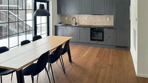 A modern kitchen with grey cabinets, a wooden dining table, and black chairs. - Stunning apartment in Idre with sauna (Idre)