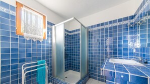 Een badkamer met blauwe tegels, een douche met glazen wand, een witte wastafel en een handdoekhouder.