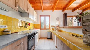 Een keuken met houten kasten, een betegelde spatwand en een accentmuur van steen.