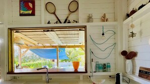 A kitchen with a large window, a sink, and a countertop with various items.