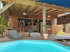 A wooden cabin with a pool, outdoor seating, and a dining area. - Villa Ekinos is ideally located within walking distance of the beaches. (Le Moule)