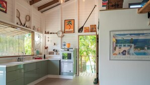 A kitchen with a large island, a refrigerator, and a dining area with a view of the outdoors.