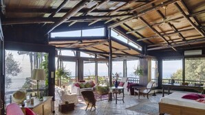 A spacious room with a high ceiling, large windows, and a cozy seating area with a sofa and chairs.