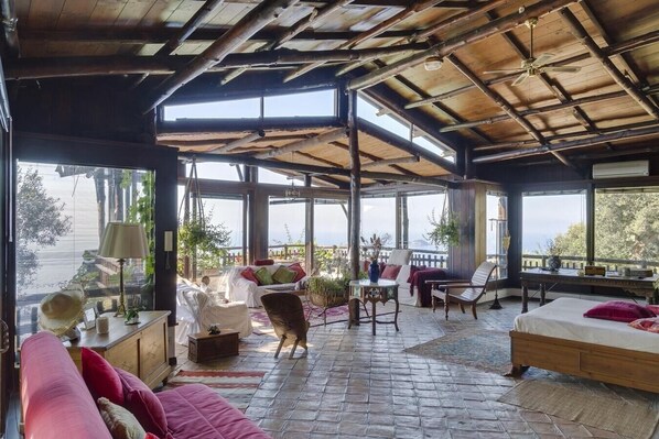 A spacious room with a high ceiling, large windows, and a cozy seating area with a sofa and chairs.