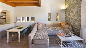 Ein modernes Wohnzimmer mit Holzbalkendecke, einer Sofagarnitur, einem Esstisch und gerahmten Kunstwerken an der Wand.