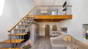 Ein modernes Interieur mit einer Holztreppe, einem Essbereich und einem Wohnzimmer mit einer Couch und Wandbildern.