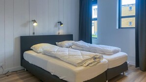 A double bed with white bedding, a dark headboard, and two bedside lamps.