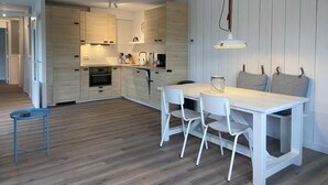 A modern kitchen with wooden cabinets, a central island, and a dining area with a white table and chairs.
