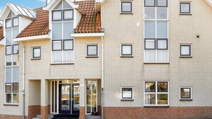 A multi-story residential building with a brick facade, multiple windows, and a front entrance with steps.