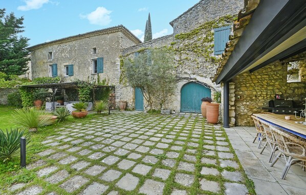 A courtyard with stone paving, a rustic building with a stone wall, and outdoor furniture. - Amazing home in Lussan (Lussan)