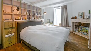 Ein Schlafzimmer mit einem großen Bett, einem Bücherregal, einem Schreibtisch und einem Kamin.