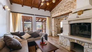 A cozy living room with a stone fireplace, wooden beams, and a comfortable sofa. - Stunning home in Valtura (Valtura)