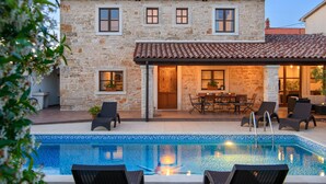 A stone building with a pool, outdoor seating, and a door leading to a covered patio. - Stunning home in Valtura (Valtura)