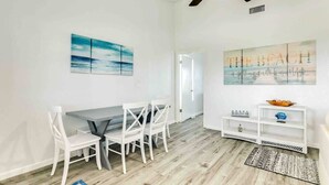 Un comedor con una mesa y sillas, un ventilador de techo y obras de arte en las paredes.