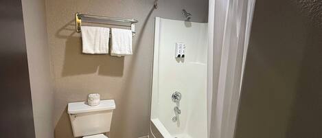 A bathroom with a toilet, a shower, and a towel rack with two towels.