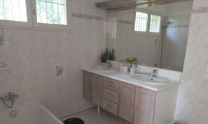 Ein Badezimmer mit zwei Waschbecken, einer Dusche und einem großen Spiegel.