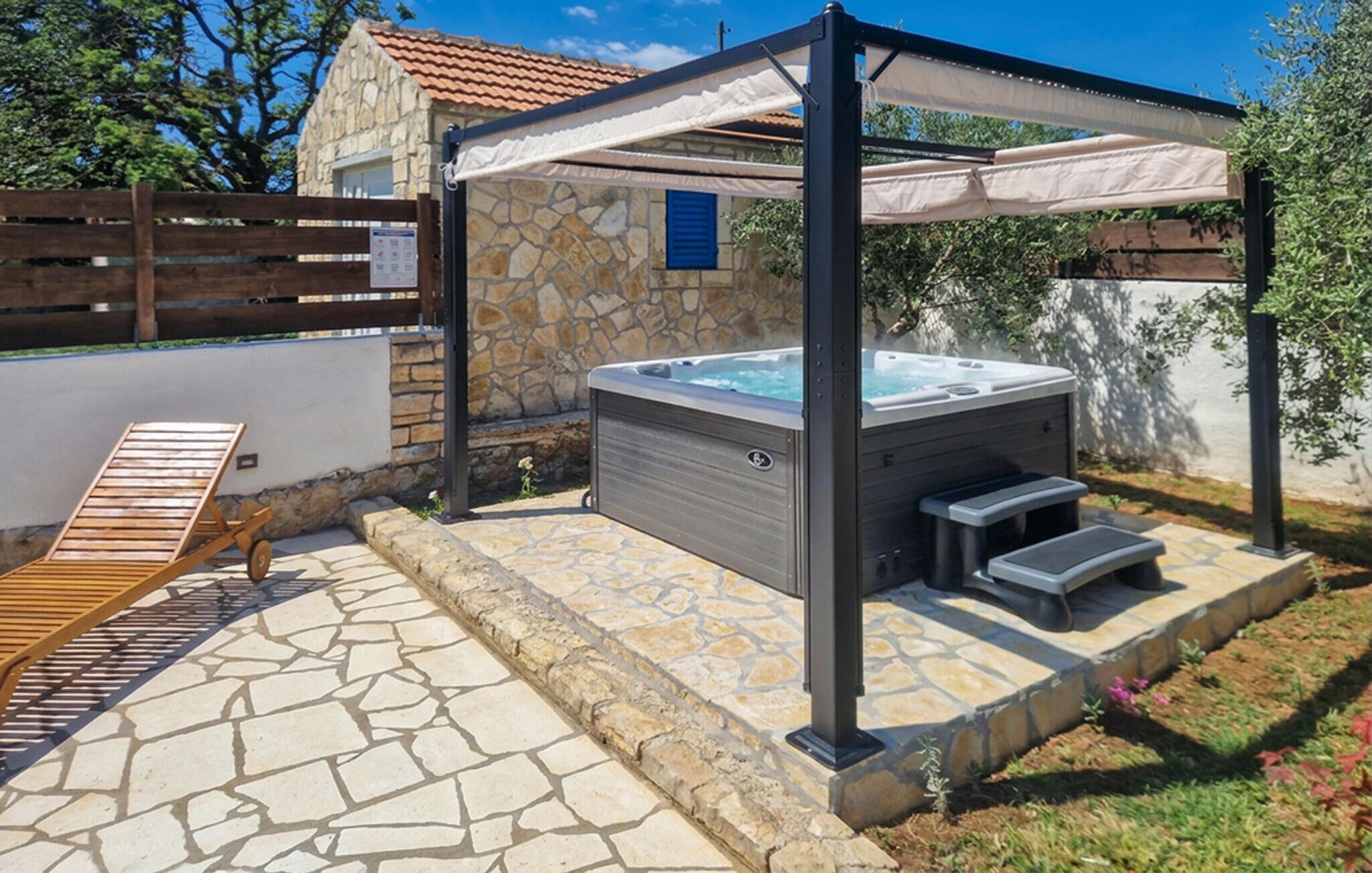 A hot tub under a pergola with stone walls and a wooden deck.