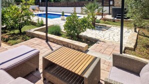 Un espace patio aménagé avec des meubles en osier, une piscine et un chemin en pierre.