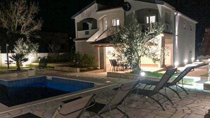 Une maison moderne dotée d’une piscine, d’un espace salon extérieur et d’un patio bien éclairé.