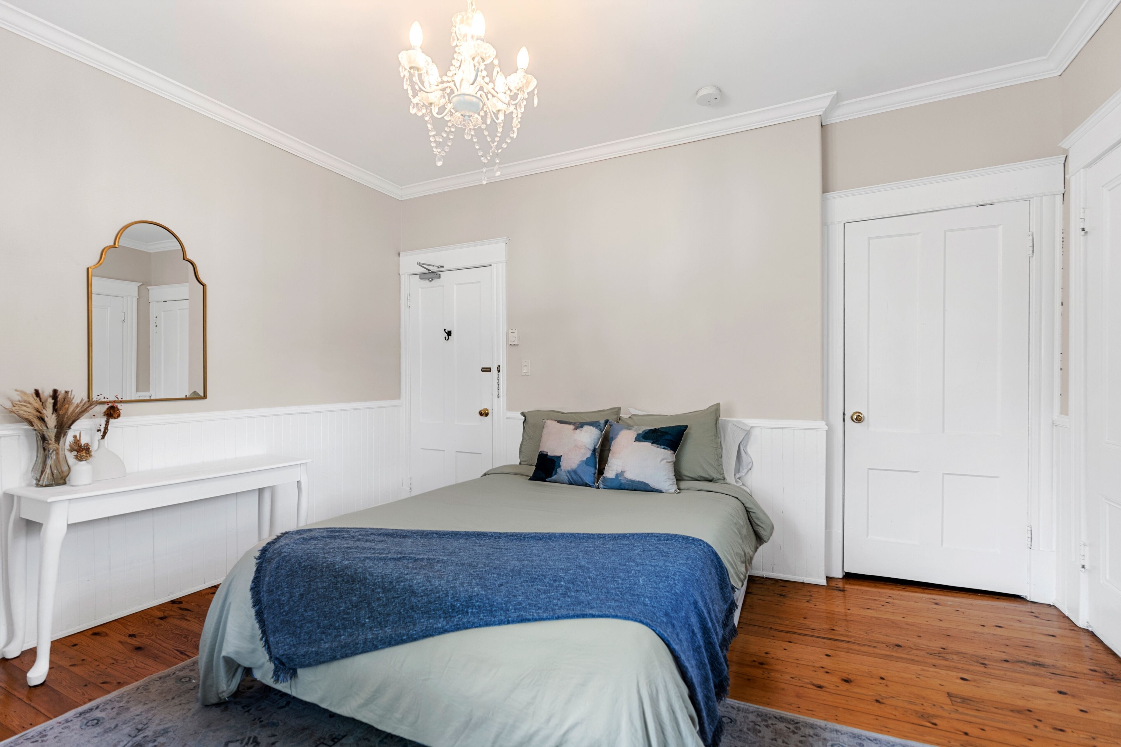 Un dormitorio con cama, cómoda, espejo y candelabro.