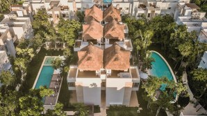 Ein Resort mit mehreren Gebäuden, einem zentralen Schwimmbad und umgebender Grünfläche.