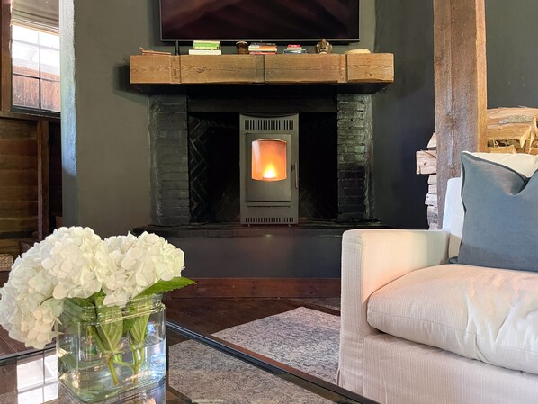 A living room with a stone fireplace, a television mounted above it, and a white sofa.