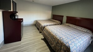 A hotel room with two beds, a desk with a flat-screen TV, and a ceiling light. - La Familia Stay Inn (Quincy)