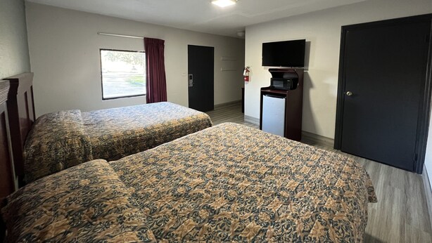 A hotel room with two beds, a TV, a microwave, and a door. - La Familia Stay Inn (Quincy)