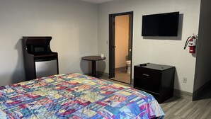 A hotel room with a bed, a desk, a microwave, a television, and a fire extinguisher. - La Familia Stay Inn (Quincy)