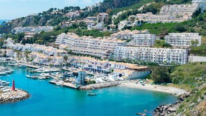 A coastal town with a marina, white buildings, and a hillside with greenery. - Apartment 'Icon Marina B' with Sea View, Wi-Fi and Air Conditioning (La Herradura)