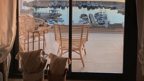 A balcony with wicker chairs and a table, overlooking a marina with boats and a sunset view. - Apartment 'Icon Marina B' with Sea View, Wi-Fi and Air Conditioning (La Herradura)